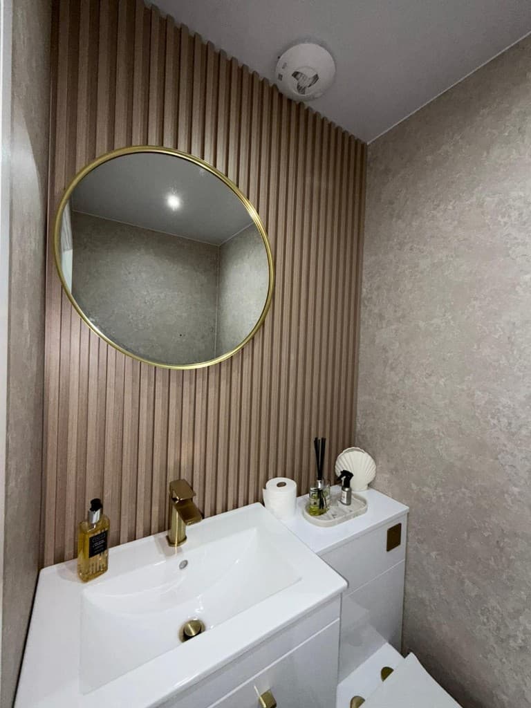 Open-plan kitchen and living area with marble countertops, gold hardware, and a styled grey sofa after turnover cleaning