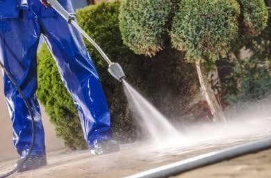 Close-up of a high-pressure water spray cleaning pale stone paving slabs on an outdoor patio