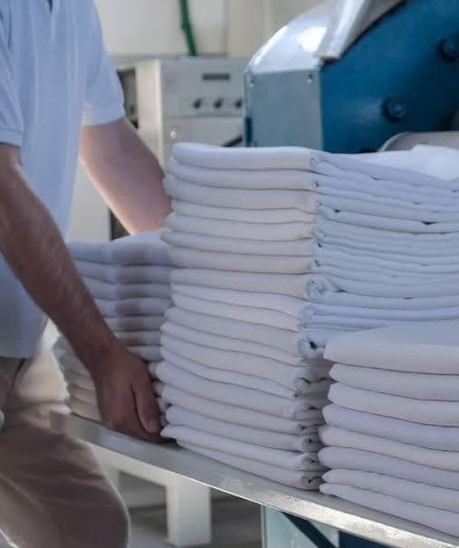 Neat stacks of freshly laundered white linens prepared in a commercial laundry facility